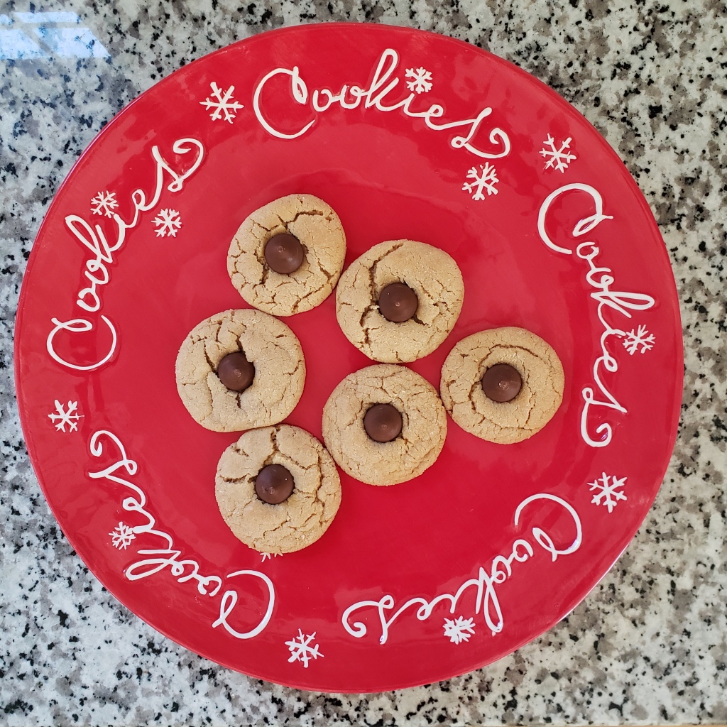 peanut butter blossom cookies on a red tray with white words and snowflakes